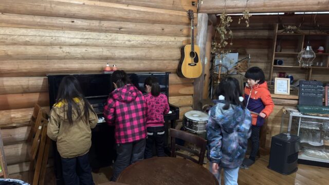 ロッジでピアノを弾く子どもたち