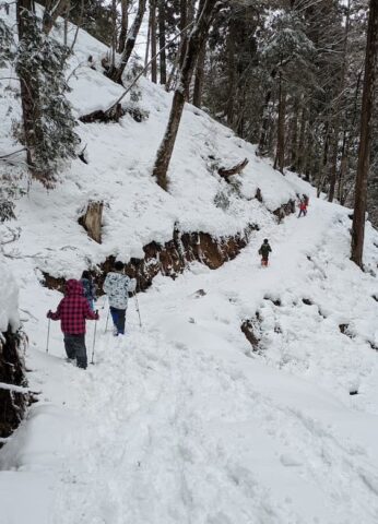 スノーシューを履いて雪山を歩く子どもたち